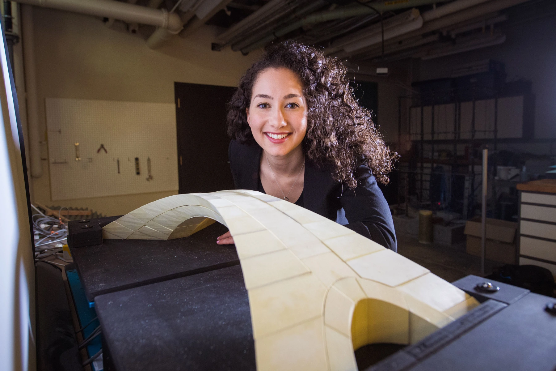 Karly Bast behind the physical research model of Leonardo’s bridge, with its arch and spreading supports on a workbench.